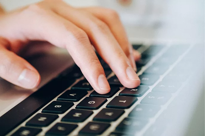 Main en train de taper sur un clavier d’ordinateur portable, illustrant l’expertise informatique d’ADMX.